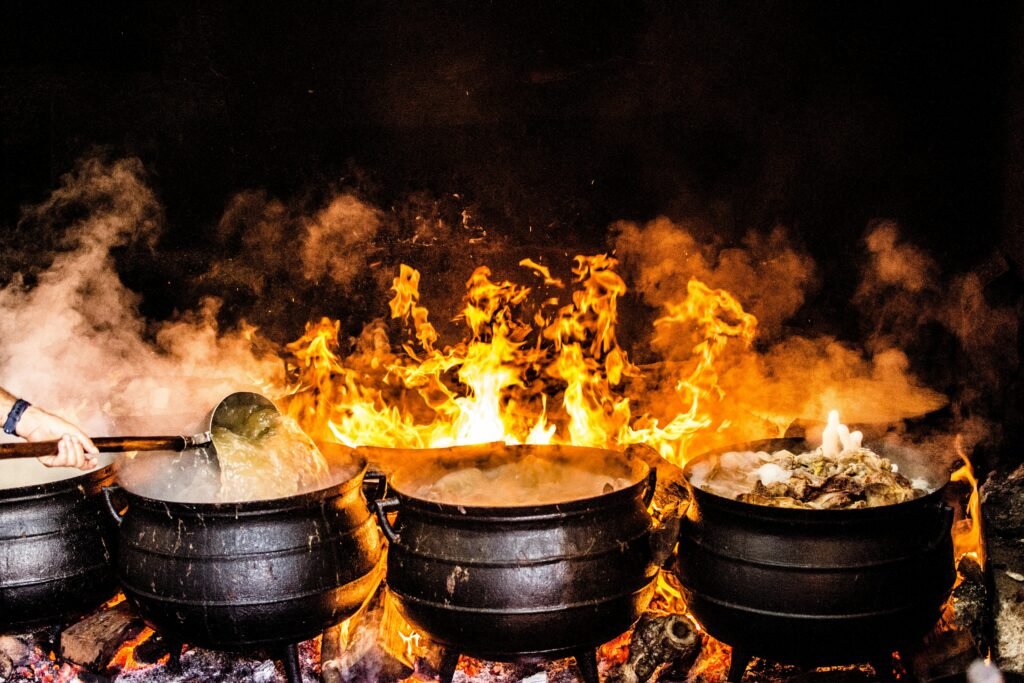 Vibrant outdoor cooking scene with large pots over open flame, showcasing traditional Açores methods.